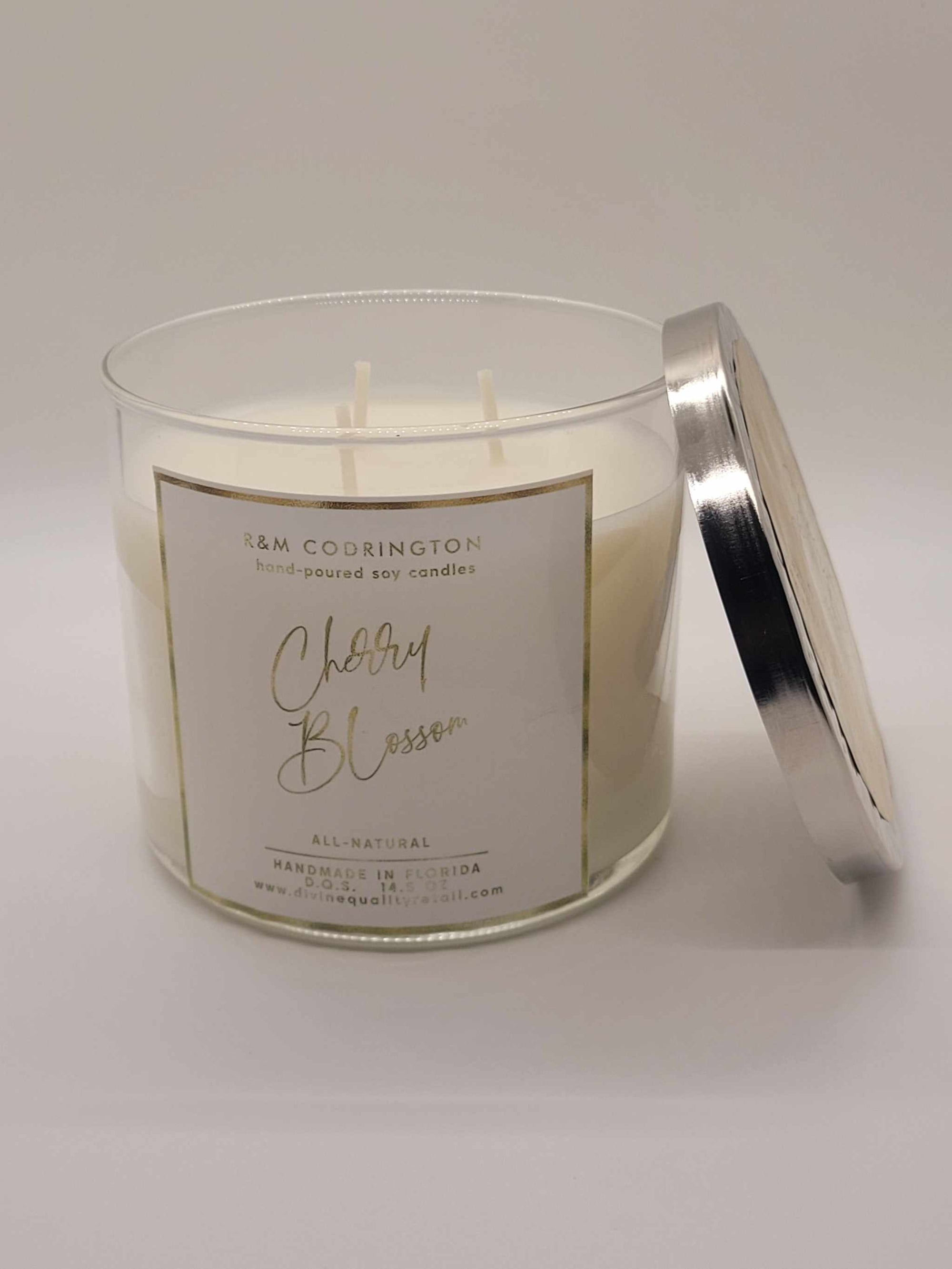 Cherry Blossom Scented Candles in clear glass jar with silver lid, three wicks, and floral fragrance label